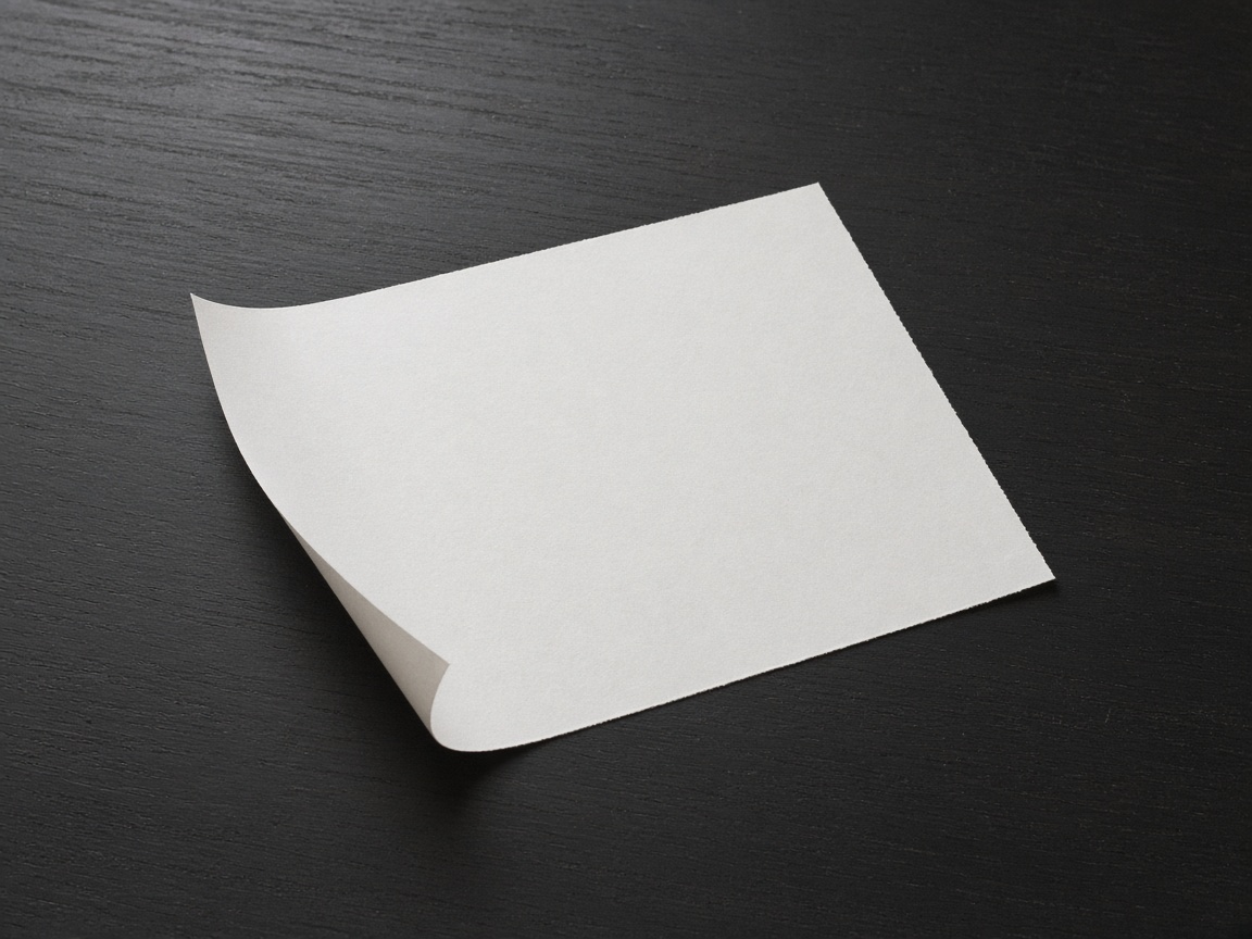 One thin blank sheet lies slightly curled on a dark desk.