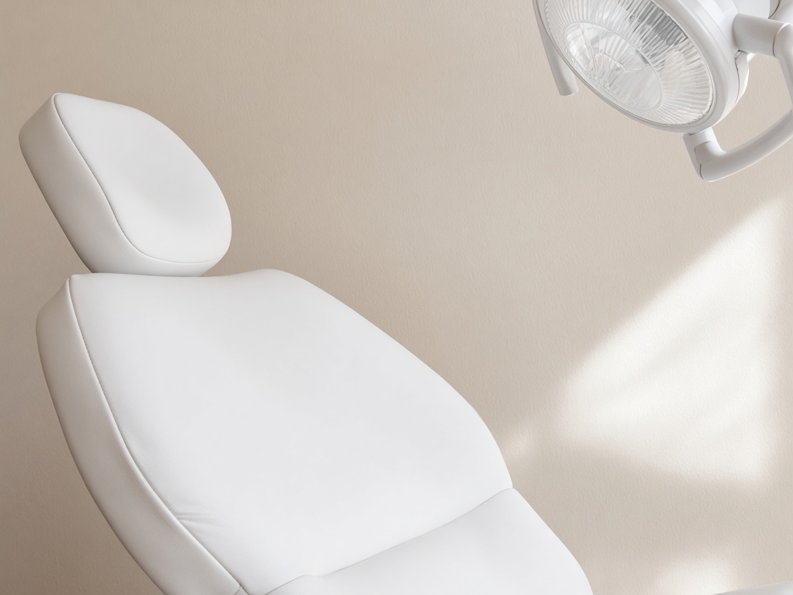 A close view of a white dental-chair headrest with part of a round operating light above it.