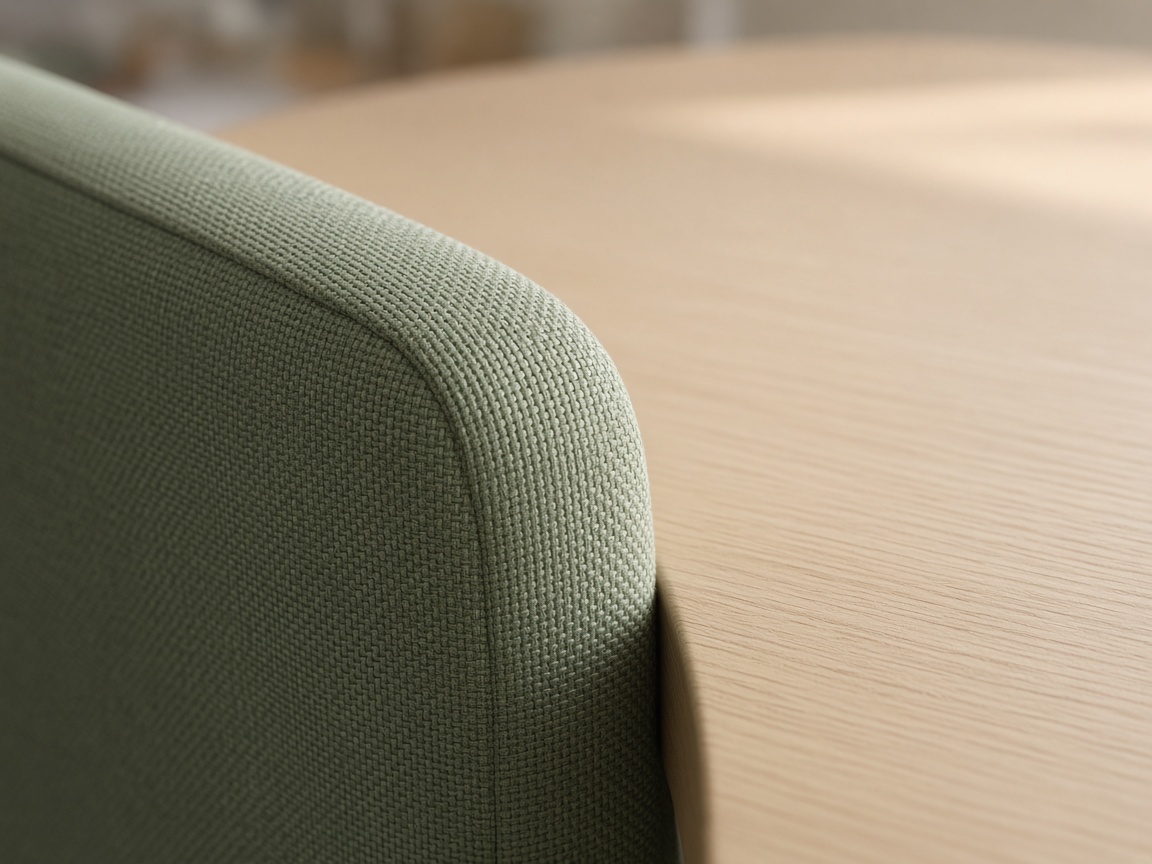 Close view of sage-green chair upholstery against a smooth light wood tabletop.