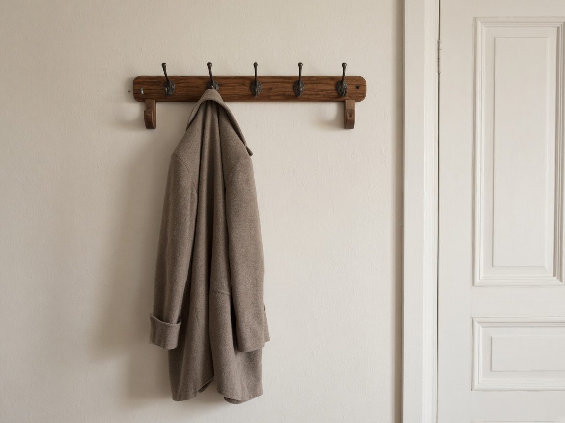 One coat on a rack with several empty hooks.