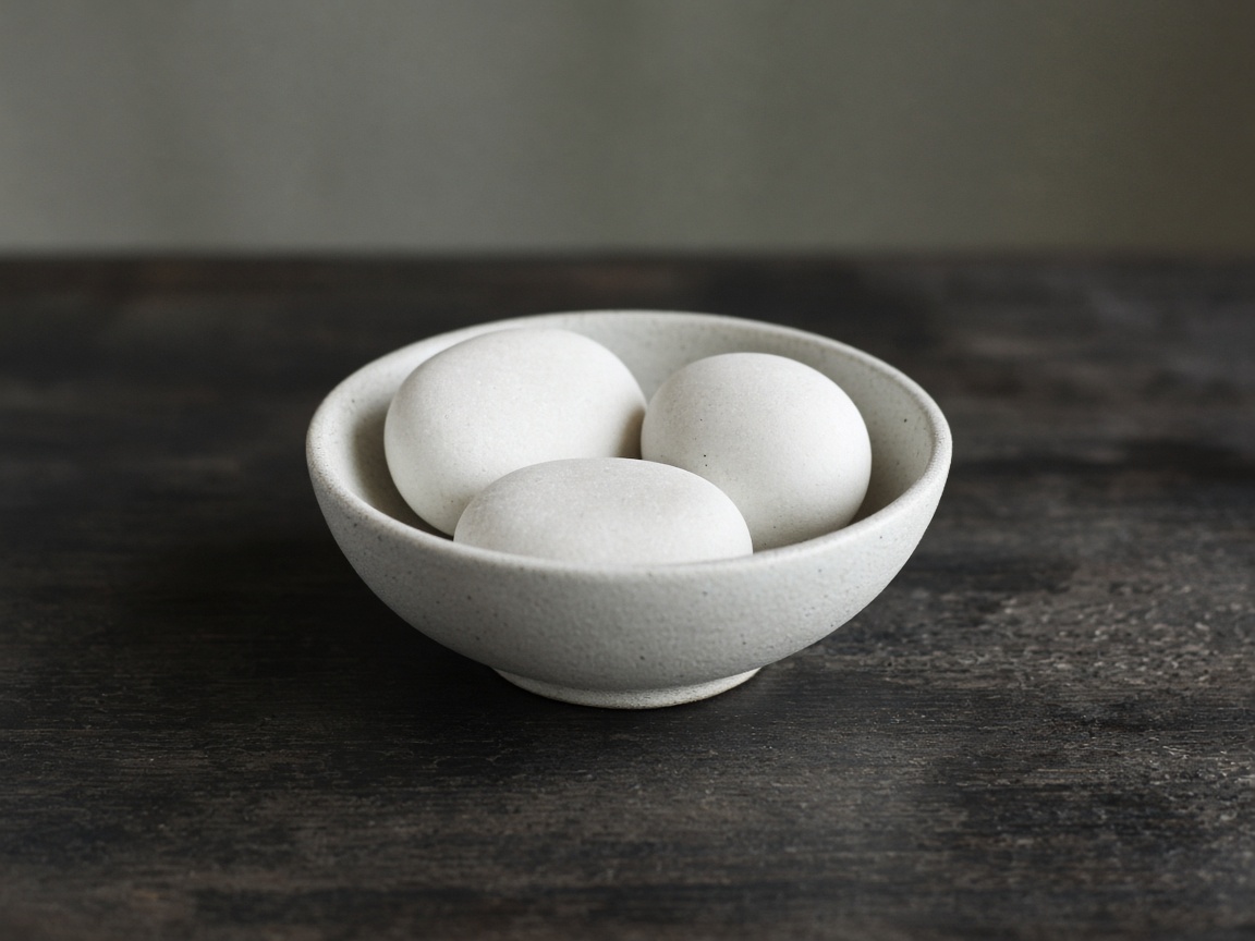Three white stones rest in a ceramic bowl.